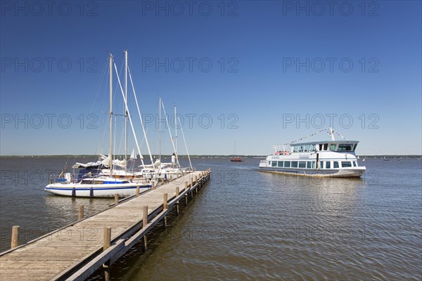 Sailing boats moored at jetty and sightseeing boat on Lake Steinhude