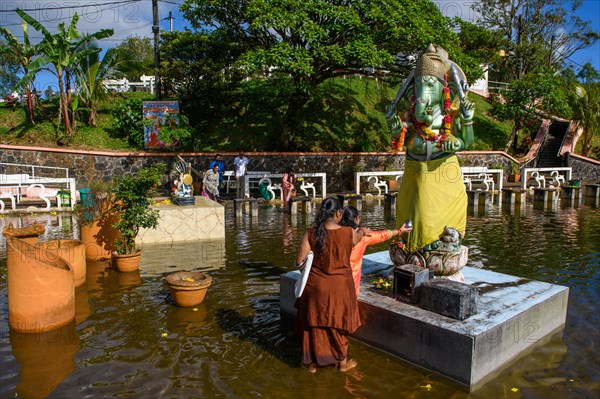 Woman in traditional Indian dress standing in Sacred Lake offering sacrifice to God deity in elephant shape figure of elephant elephant god Ganesha at religious site largest Hindu sanctuary sanctuary for religion Hinduism outside India for devout Hindu Hindus