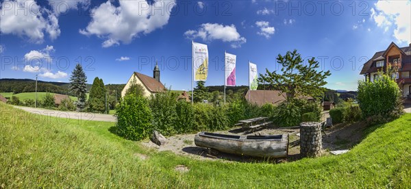 Rest area for hikers with flags and the pilgrimage church of Oberbiederbach in Biederbach