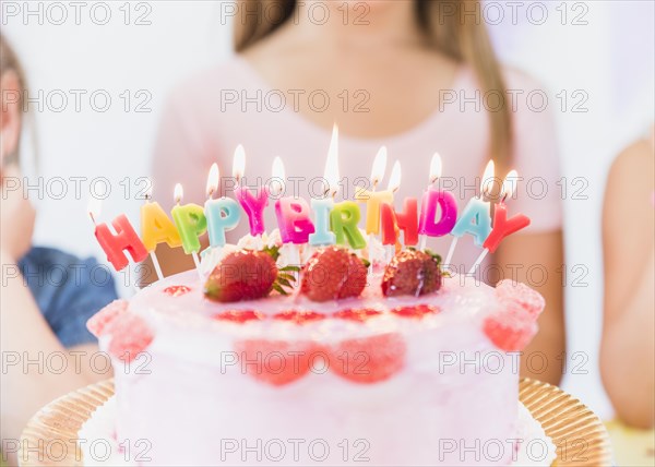 Close up colorful glowing birthday candles strawberry topping cake