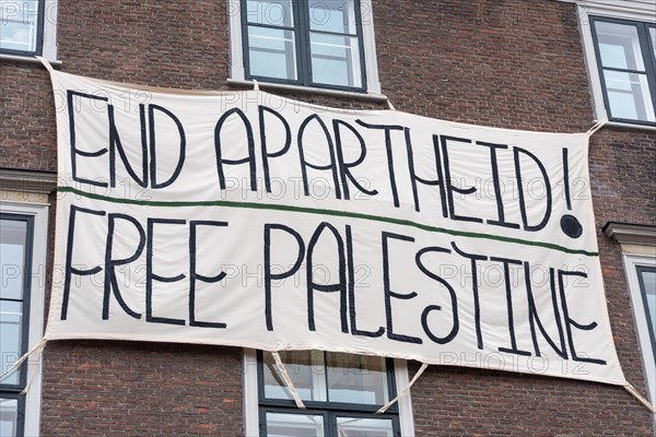 A banner with the words End Apartheid! hangs on a building. Free Palestine