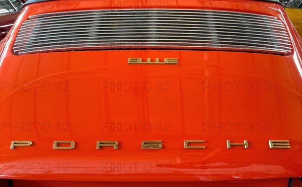 Rear of classic car Porsche 911 E from the 60s in orange colour with typical radiator grille