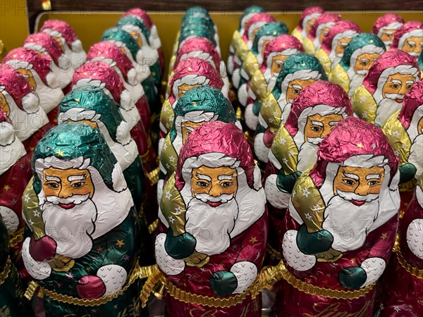 Display in shelf of wholesale of chocolate Father Christmases Nikolaus Nikolaeuse colour old pink Guen of staniol paper of chocolate brand Lindt arranged like army of Father Christmas