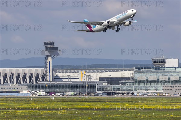 Aircraft taking off with terminal and tower. D-AIKB