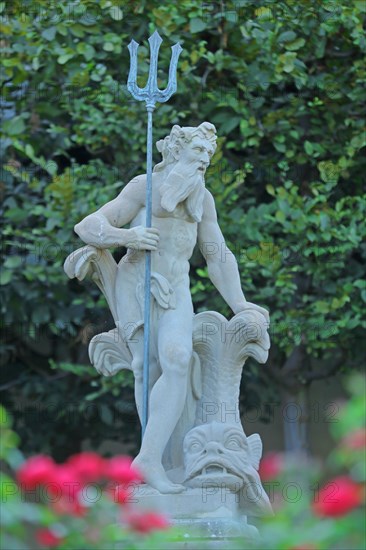 Sculpture Neptune with trident and fish figure in baroque rose garden