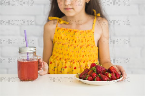 Close up girl holding plate strawberries smoothies jar