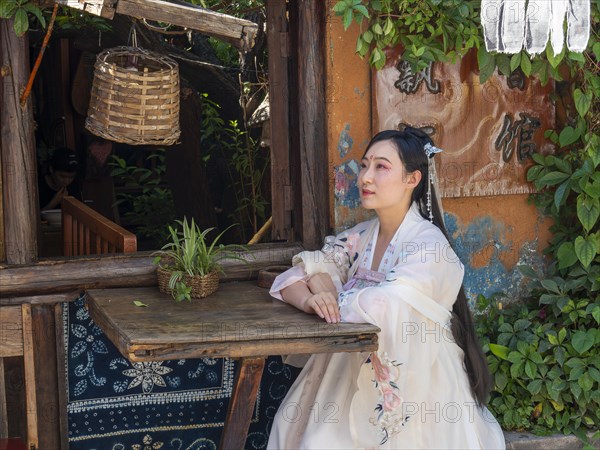 Woman in Chinese nostalgia with old luxurious white dress in front of old house