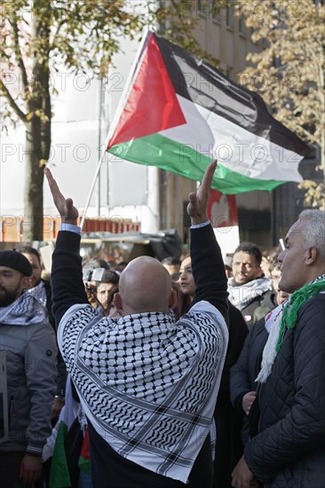 Demo participant with Palestinian scarf claps hands