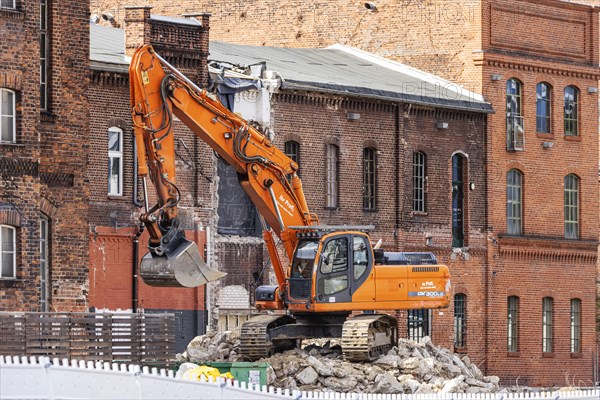 Demolition excavator in front of historic brick buildings