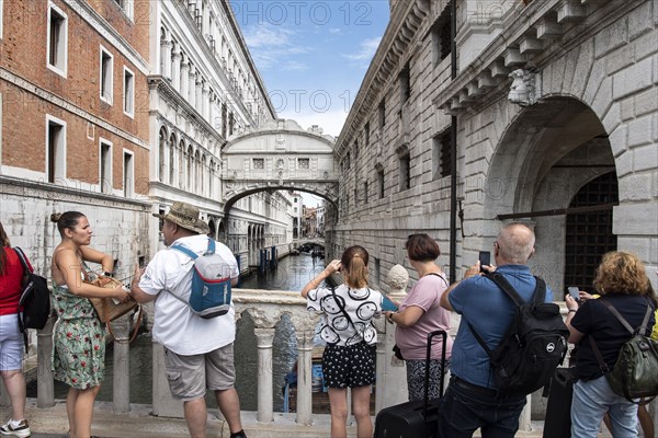 Tourists on the Ponte de Paglia visit the Bridge of Sighs