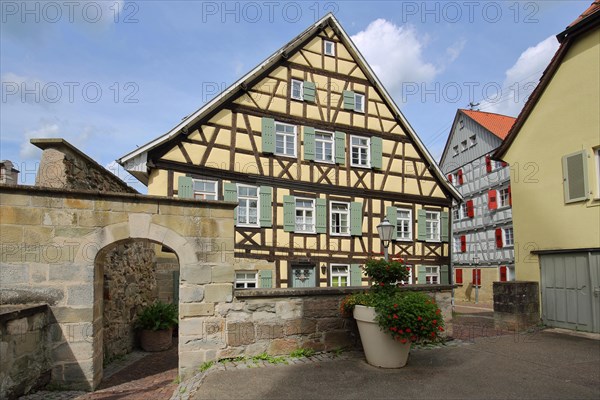 Historic town wall with archway and half-timbered house