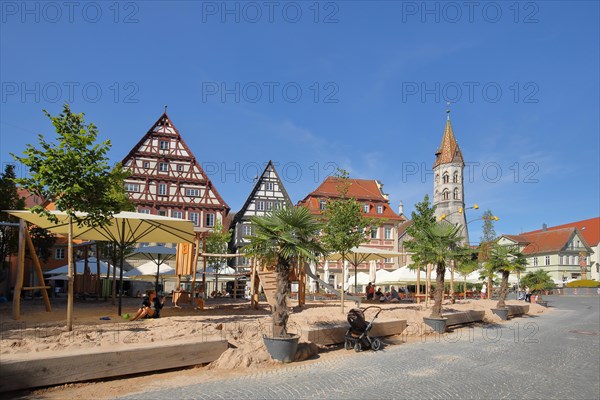 Sandy beach beach and children's playground with neo-Romanesque St. John's Church on the market square