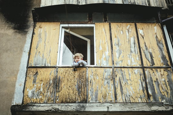 A boy looks out of the window of a flat of a building in danger of collapsing in Akarmara