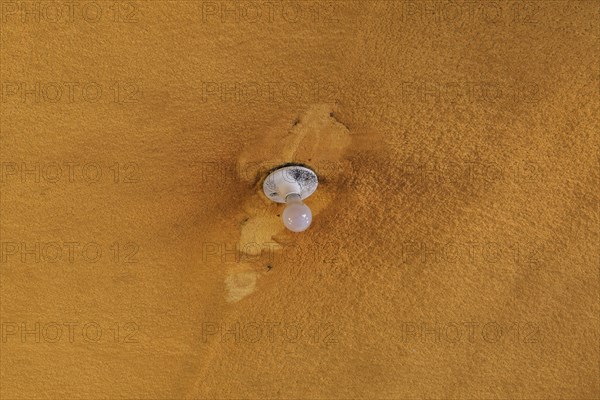 Lightbulb and socket on ceiling covered with foam insulation