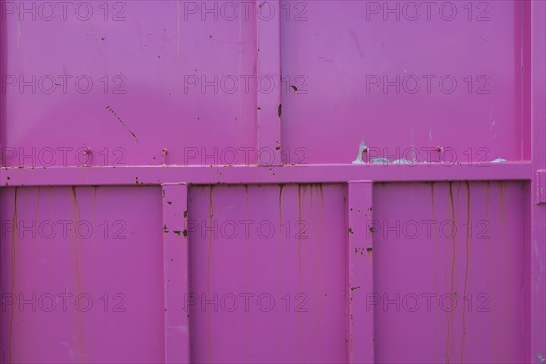 Pink painted metal container with rust stains