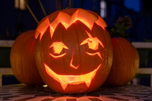 Carved pumpkin stands on a balcony on Halloween evening