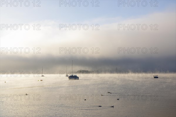 Fog over Lake Constance on an autumn morning with boats