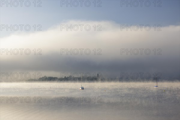 Fog over Lake Constance on an autumn morning with boats