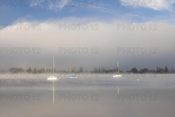 Fog over Lake Constance on an autumn morning with boats