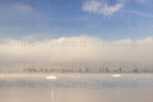 Fog over Lake Constance on an autumn morning with boats