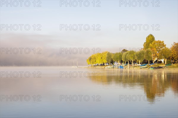 Fog over Lake Constance on an autumn morning with boats