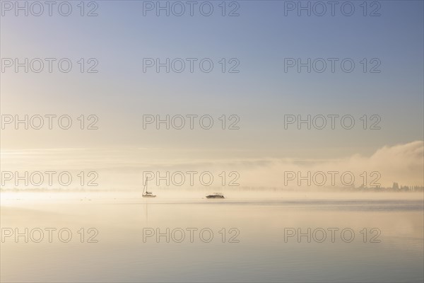 Fog over Lake Constance on an autumn morning with boats