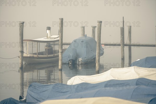 Fog over Lake Constance on an autumn morning with boats and old steamboat