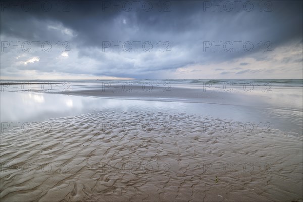 Evening mood with cloudy sky and rain on the beach and in the dunes of De Panne