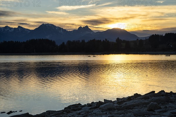 Lake Forggensee in Allgäu in autumn at sunset. Rock formations in the foreground