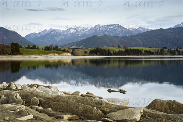 Lake Forggensee in the Allgäu in autumn after sunset. Rock formations in the foreground