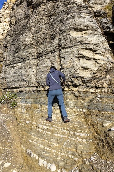 Hiker over rope-secured passage on hiking trail in Catinaccio massif