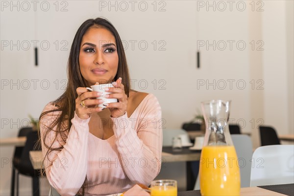 Cool and relaxed casual businesswoman drinking coffee in a luxury hotel during breakfast