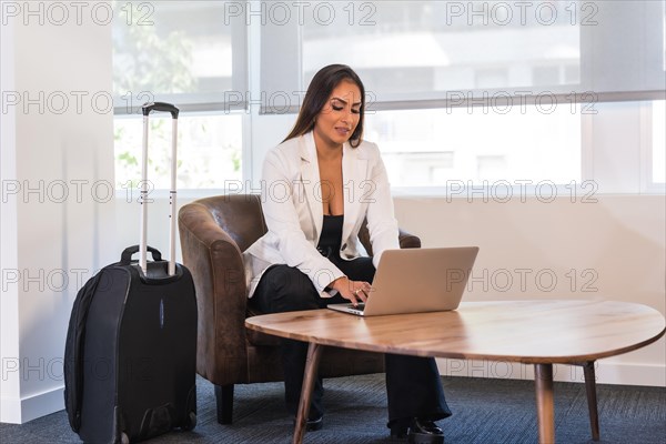 Horizontal photo with copy space of a businesswoman using laptop in a hotel waiting room