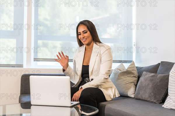 Horizontal photo with copy space of a businesswoman waving during an online business meeting using laptop