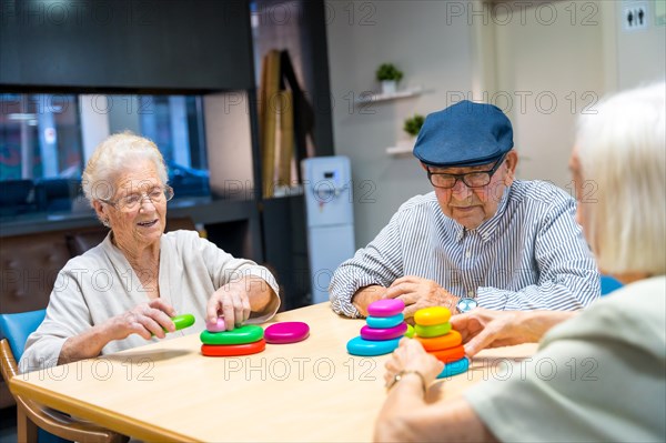 Three cute elder people playing skill games together in a nursing home