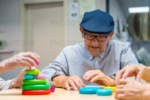 Elder man playing skill games in a nursing home next to mates