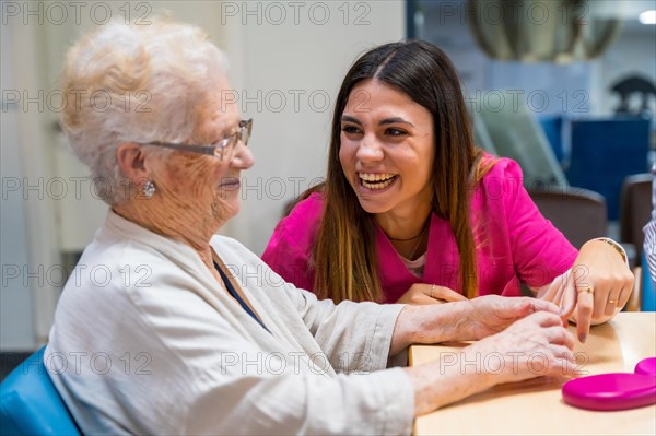 Senior woman and nurse playing board game in a nursing home