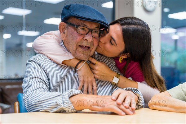 Tender moment of a nurse kissing and embracing a elder man in a geriatric