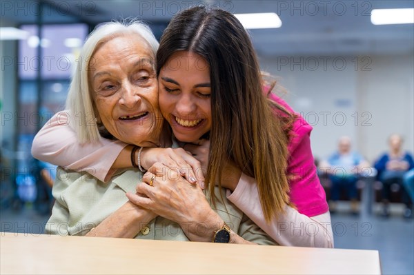 Cute moment in a nursing home between nurse and old cute woman embracing together