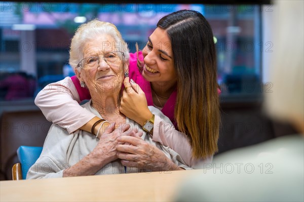 Tender moment of a happy nurse caressing and embracing an old woman in a geriatric