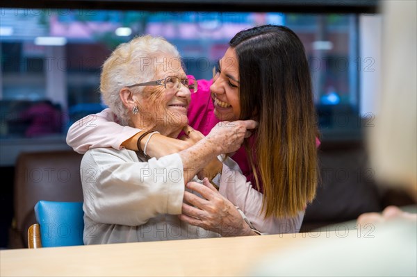 Happy moment of an elder woman and nurse embracing in a geriatric