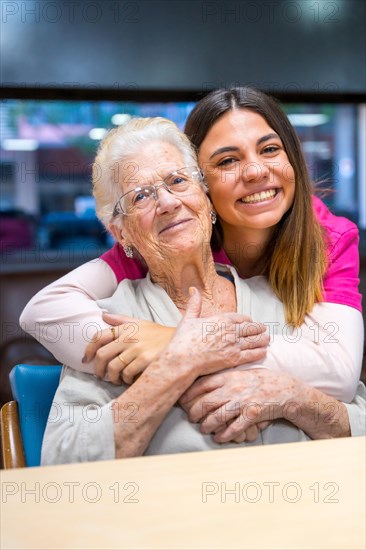 Vertical portrait of a cute nurse and an elder woman in a geriatric