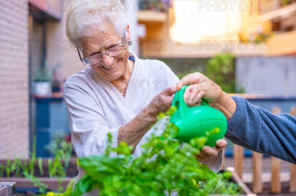 Senior woman watering plants in the backyard of a nursing home