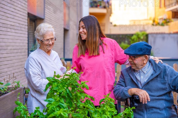 Nurse chatting with elder people in a vegetable garden in a geriatric