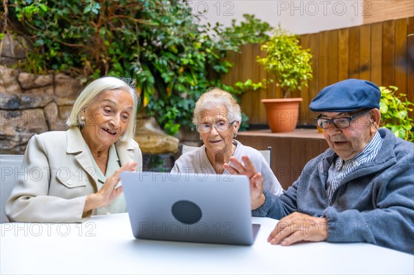 Elder people waving during a video call with laptop in a geriatric