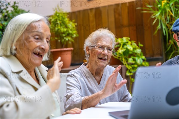 Happy women waving during a video call in a geriatric. Introducing technology to seniors