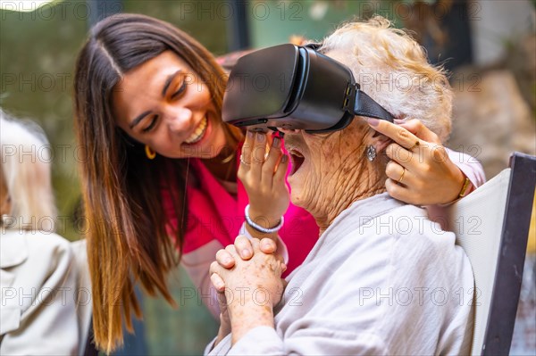 Nurse next to an amazed old woman using virtual reality goggles in a geriatric