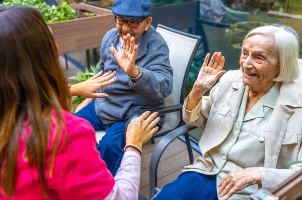 Senior people having fun with a nurse sitting outdoors on a garden in a geriatric