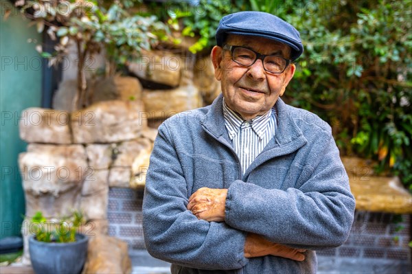 Proud senior man with beret standing with arms crossed in a geriatric