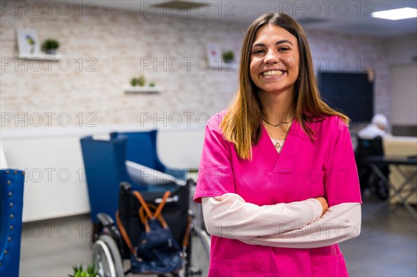 Portrait of a smiling nurse wearing pink uniform in a nursing home